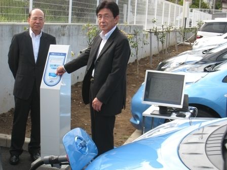 課金式充電サービスを試すJCNの武田社長(左)とファミリーマートの本多利範常務執行役員