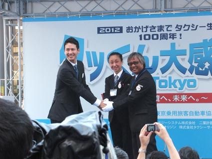 東京観光タクシーの出発式の時の川鍋・東タク協副会長と第1期認定ドライバー代表
