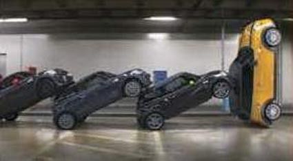 歴代MINIが立体駐車場のスロープをドミノ倒しのように倒れていき、最後に新型車が夜の街へ走り出す