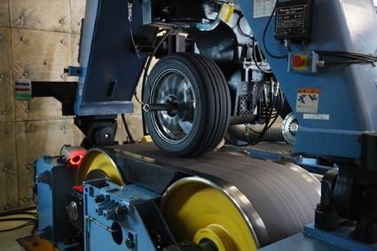 フラットベルトコーナリング試験。ステンレス板の上を回転させ、直進性や操縦安定性などの性能を評価する