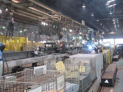 ベルトコンベヤーを流れるメーンフレームに部品を溶接する