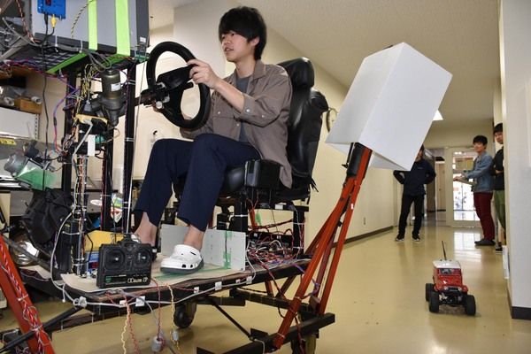 山中助教の研究室が製作したドライブシミュレーターでラジコンカー(写真右下)を操る装置。車両の遠隔操作を研究