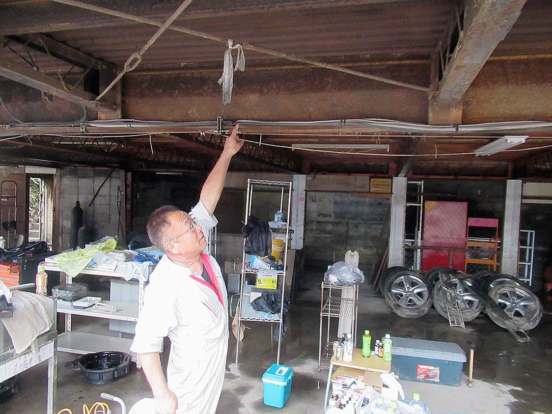 浸水した場所を指さす有川社長