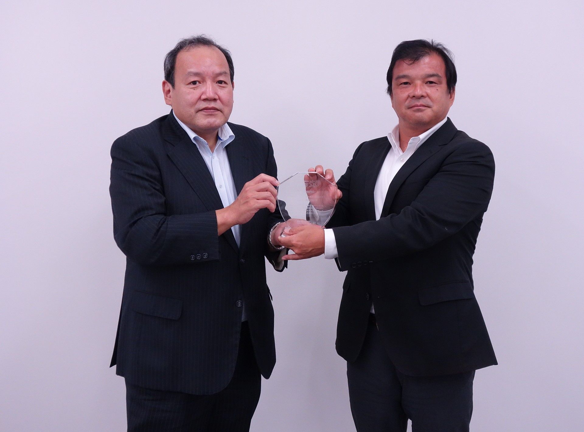 用品大賞タイヤ部門の表彰盾を持つ政友毅消費財製品企画部部長と髙橋賢治日刊自動車新聞社社長