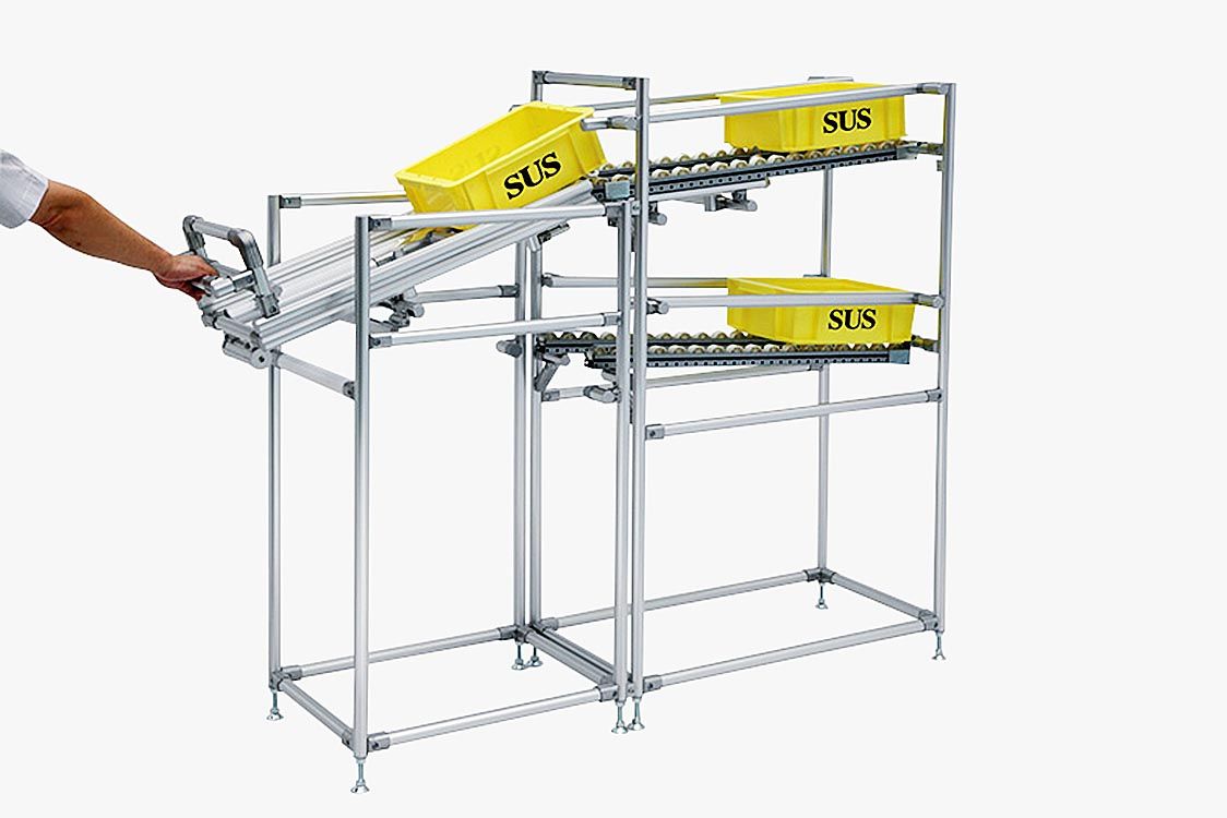 アルミフレームとアタッチメントで組み立てた「折り返しシューター」。コンテナとワークの自重でテーブルを自立、停止させ、作業後は空箱を返す仕組み