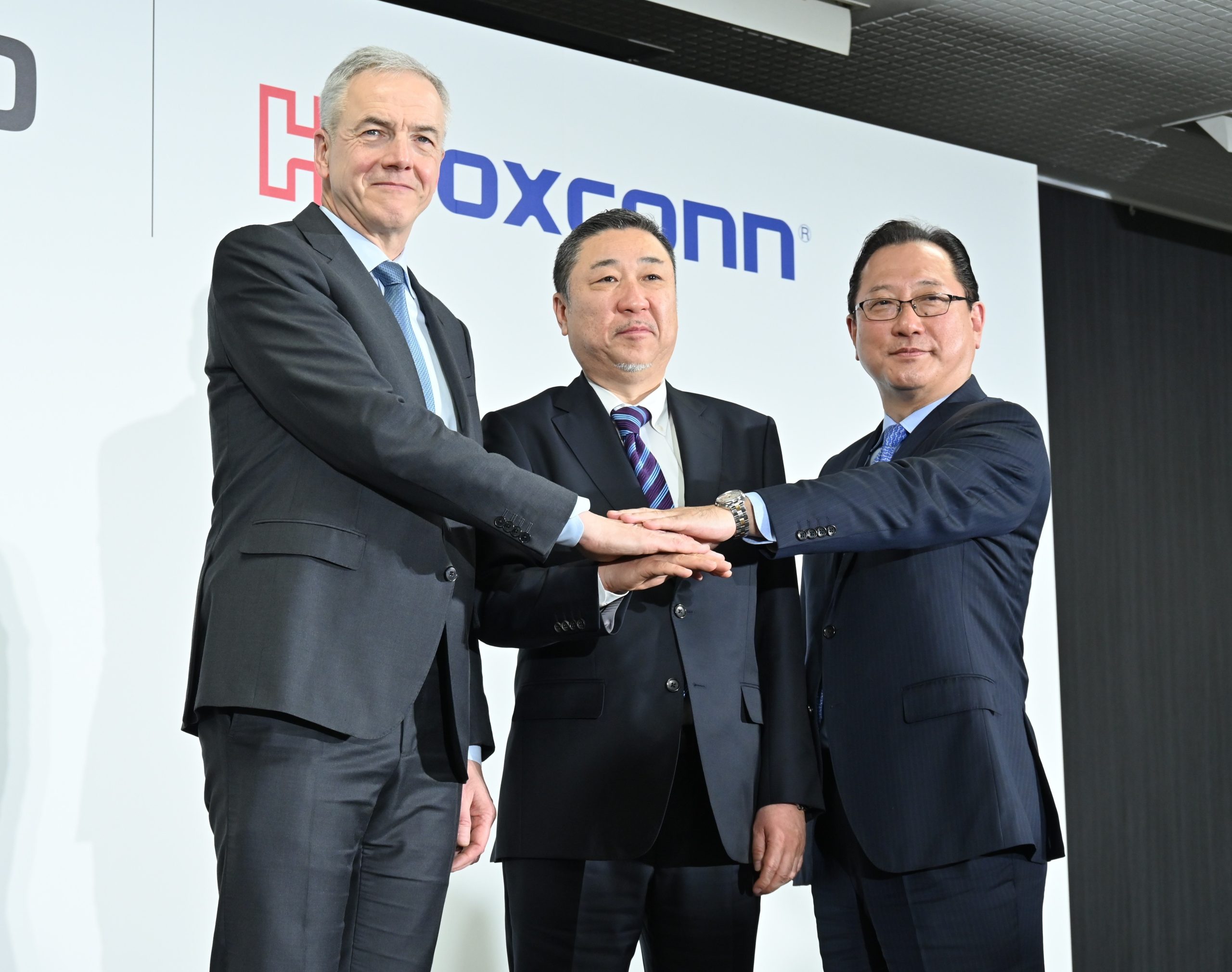 手を合わせる三菱ふそうのデッペンCEO(写真左)と高羅バス事業本部長(中央)、鴻海のEV事業の関CSO